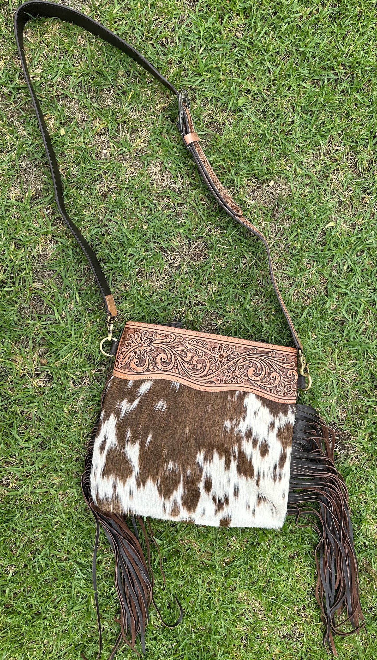 large cowhide bag with tooled shoulder strap ￼